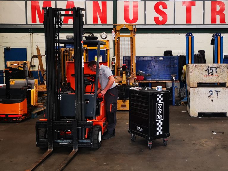 Un technicien SAV Manustra effectue l'entretien et la maintenance d'un chariot élévateur dans son atelier de manutention