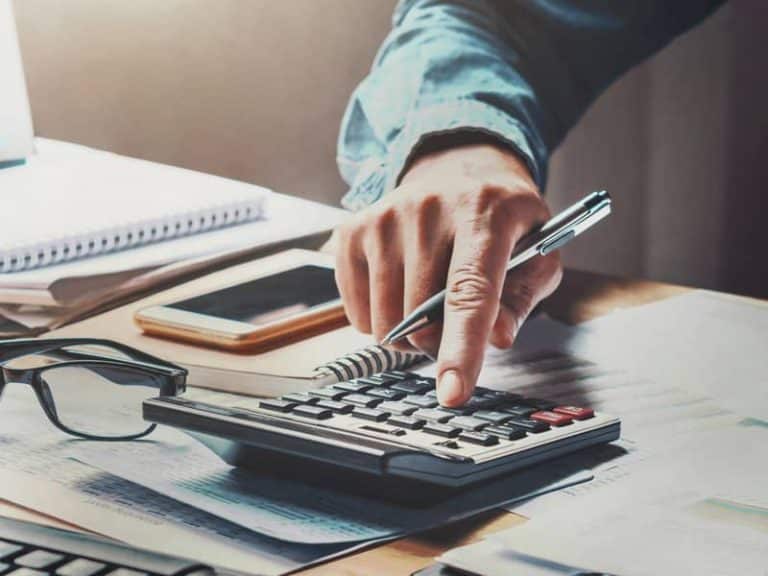 Un homme d'affaires utilisant une calculatrice avec un stylo travaillant au bureau. concept finance et comptabilité
